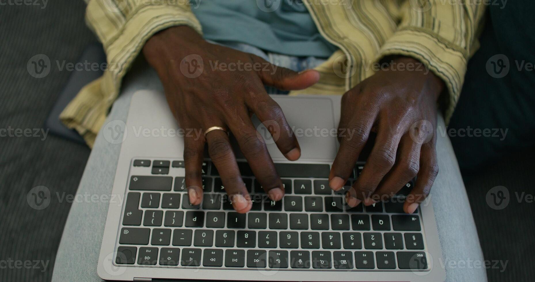 A man uses a laptop while sitting on the couch at home, close-up of his hands, an unrecognizable person. Daylight - unrecognizable photo