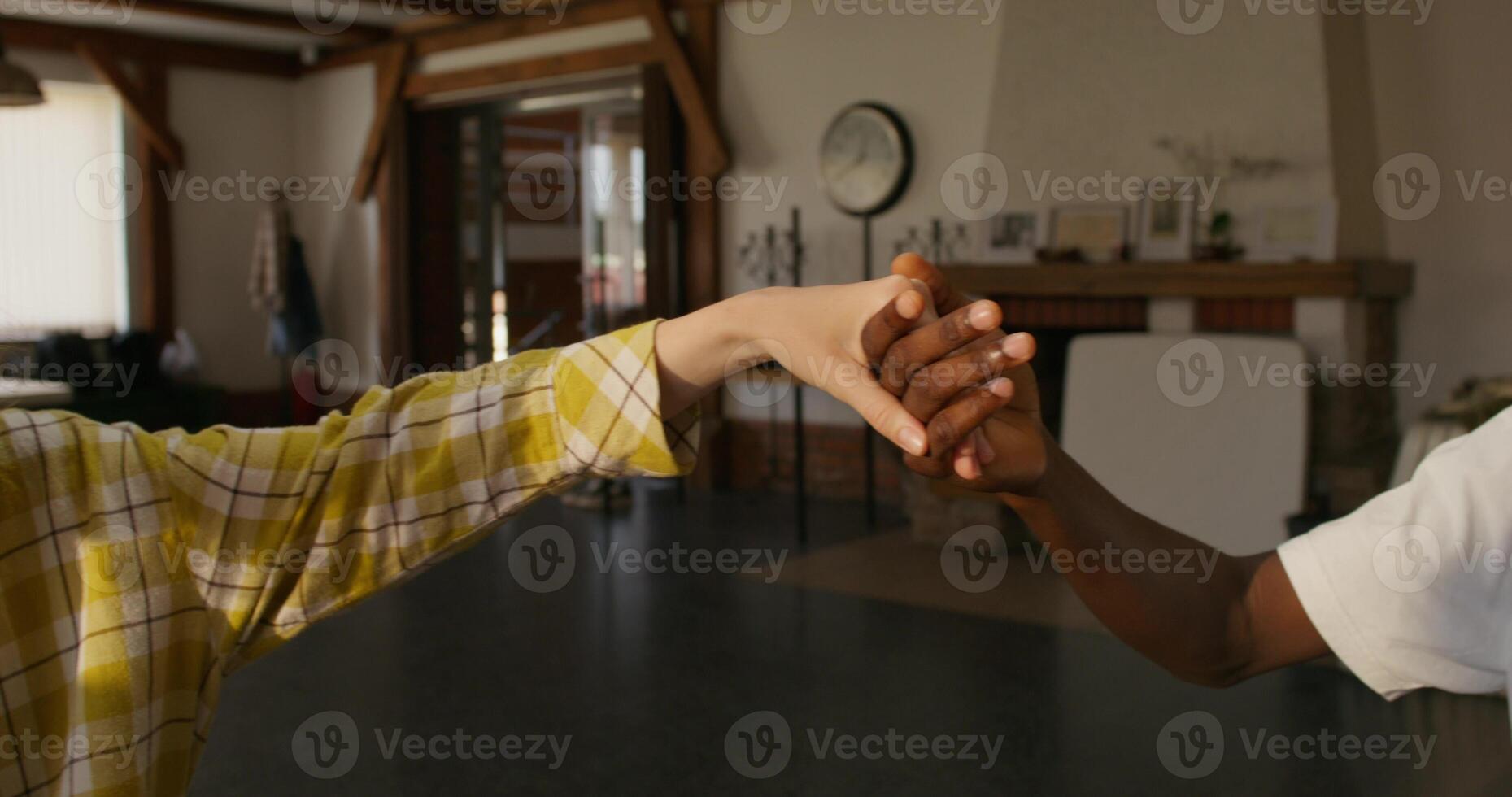 Young people of different nationalities pray holding hands, sitting at a table indoors. Daylight photo