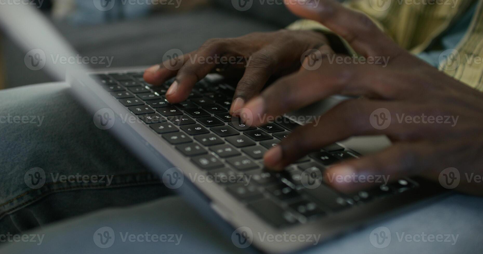 A man uses a laptop while sitting on the couch at home, close-up of his hands, an unrecognizable person. Daylight photo