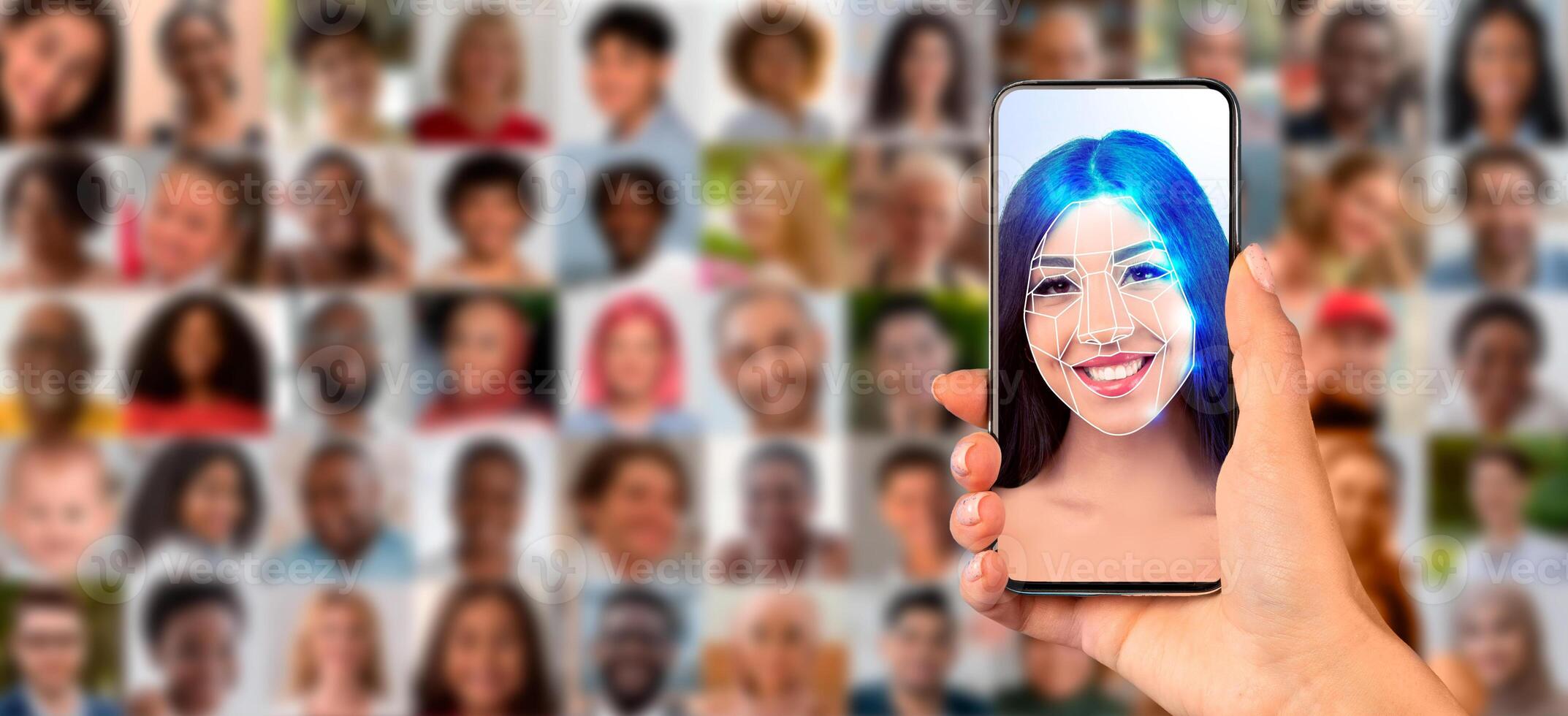 A hand holds a smartphone displaying a face scan, highlighting modern facial recognition technology. Multiple portraits are blurred in the background, showcasing diverse individuals. photo
