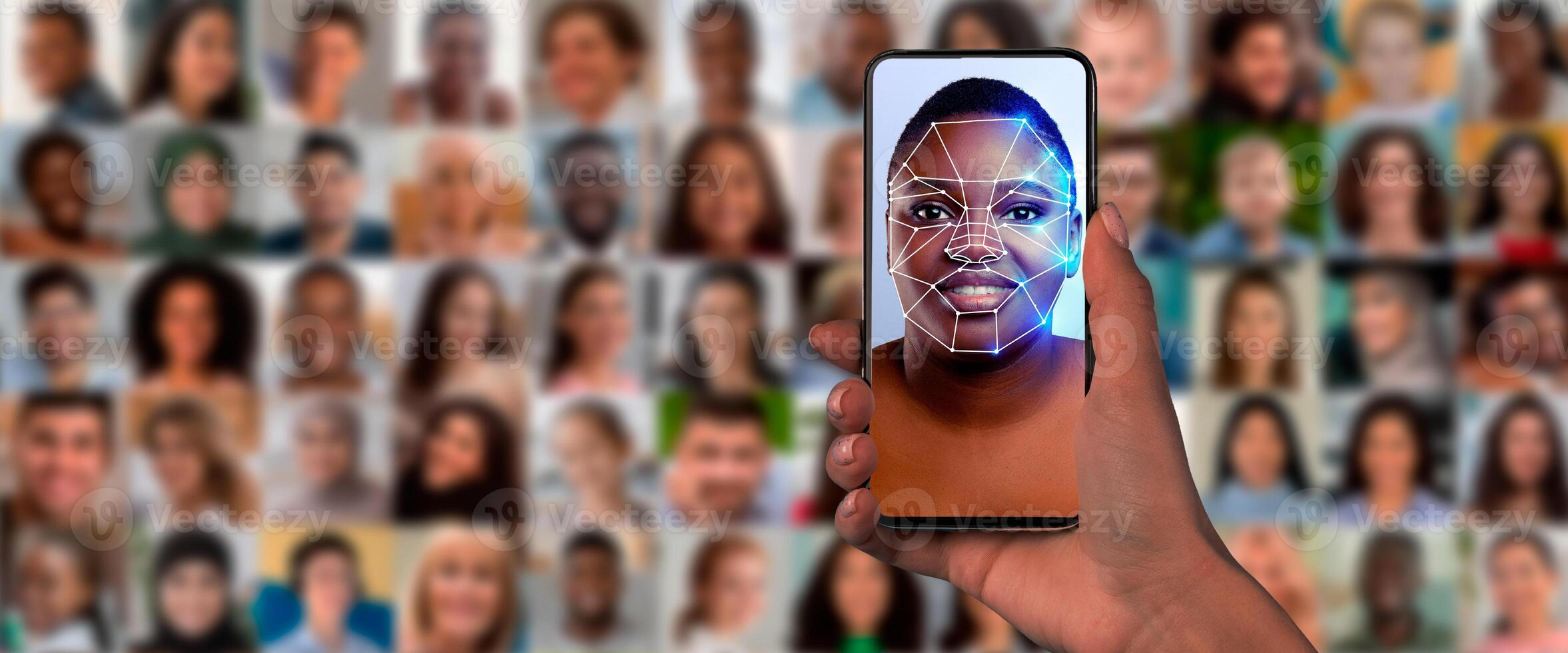 A hand holds a smartphone displaying a digital face scan. Behind, a collage of diverse faces highlights the technology's capability for identification in modern society. photo