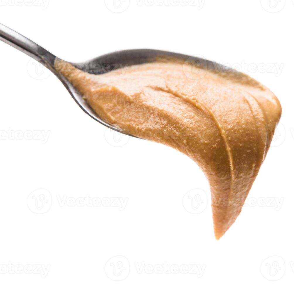 Spoon of peanut paste isolated on white background. Unhealthy fats concept photo