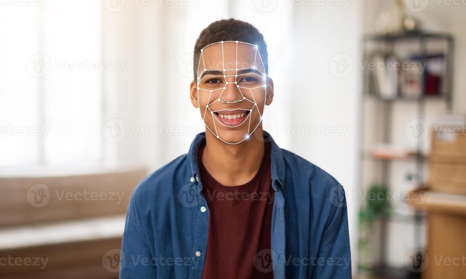 A young man participates in a facial recognition identification check in a modern, well-lit room. The technology highlights his facial features for verification purposes in today's digital landscape. photo