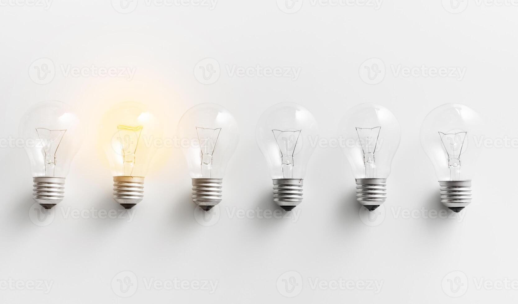 Concept for creativity, innovation and solution. Illuminated light bulb in row of dim ones on white background photo