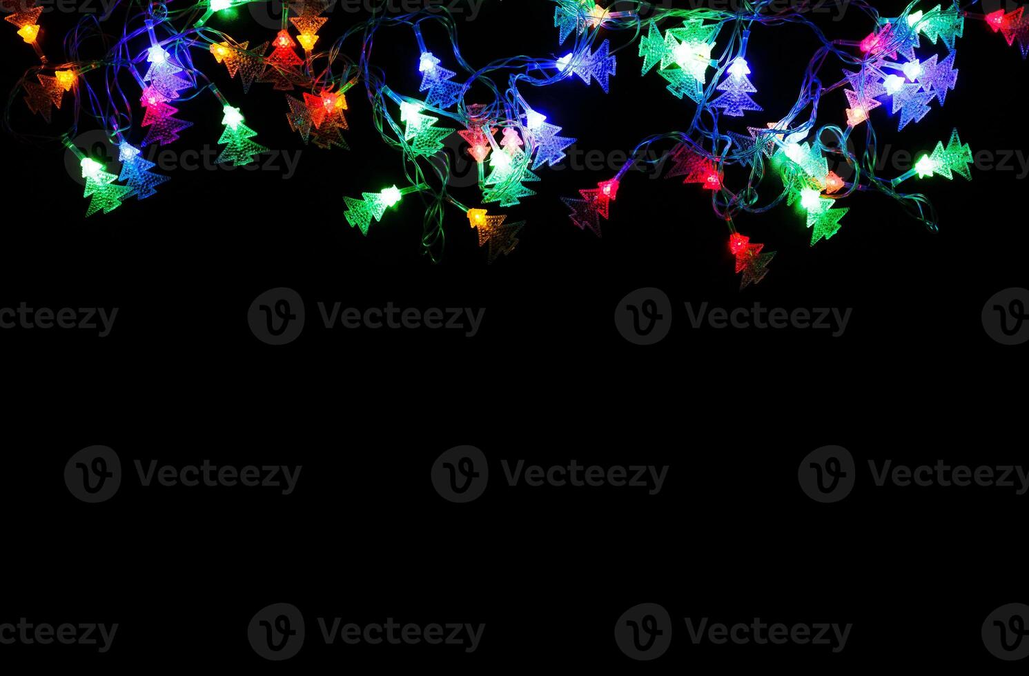 Christmas lights frame on black background. Holiday shiny garland border with copy space, top view. Xmas tree decorations, winter holidays illumination photo