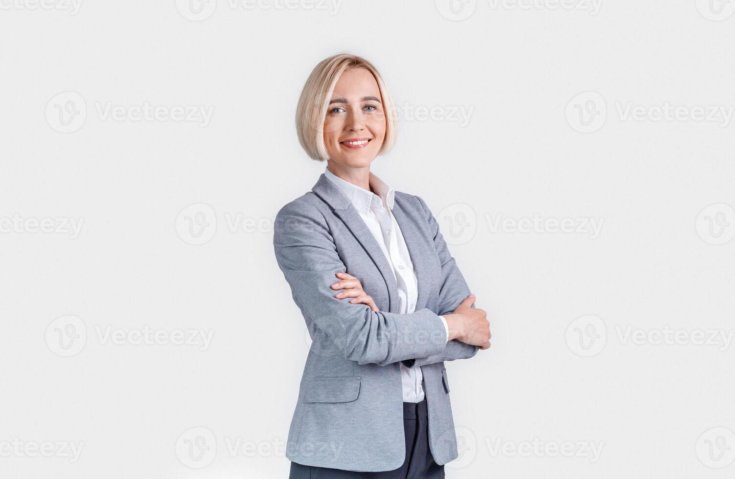 Beautiful smiling businesswoman with crossed arms on grey background photo