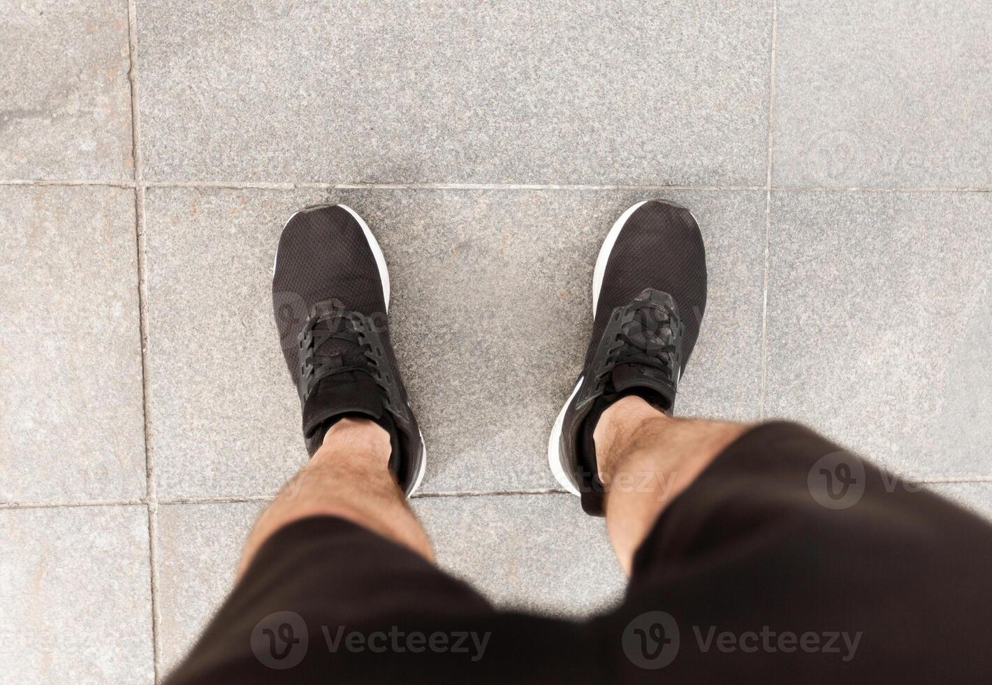 POV. Male runner looking down at his feet, wearing sports shoes footwear, ready for jogging photo