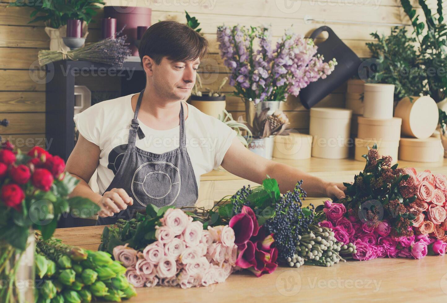 Flowers delivery shop. Florist making bouquets. Man assistant or owner in floral design studio, making decorations and arrangements. Creating order photo