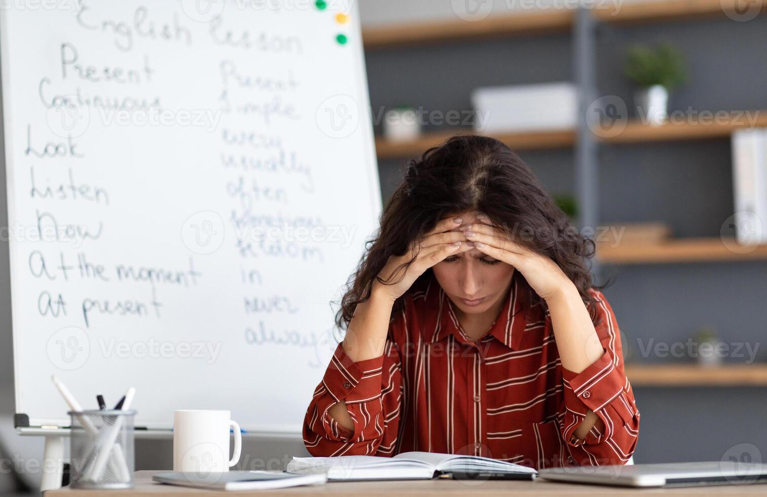 Portrait of tired concerned young lady feeling stress, tired of work upset about deadlines and troubles, suffering from headache, sitting at desk near whiteboard, thinking about problems issues photo
