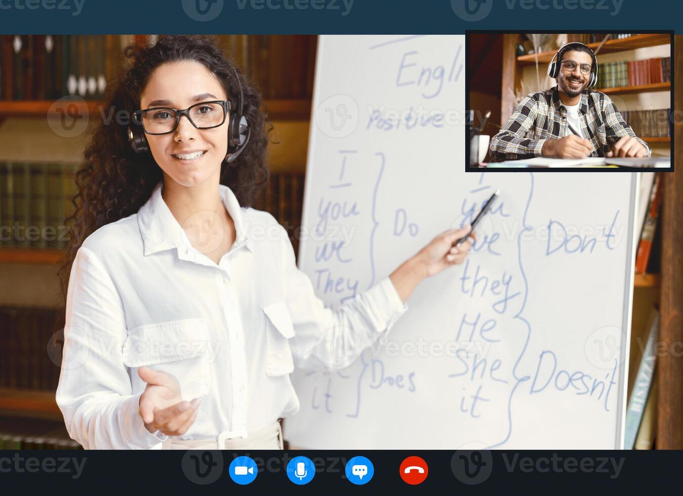 Online Tutoring. Portrait Of Woman In Glasses And Headset Having Conference, Teaching Foreign Languages, Talking To Camera During Web Call, Indian Student Sitting At Desk At Home And Writing photo