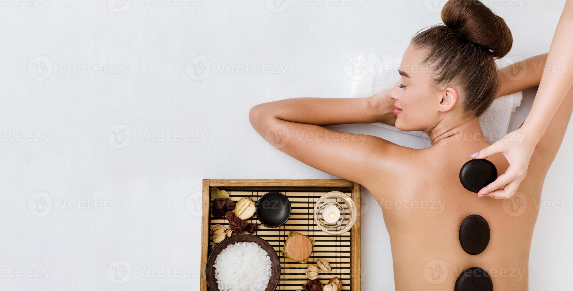 Young woman having stone massage in spa salon, top view, copy space photo