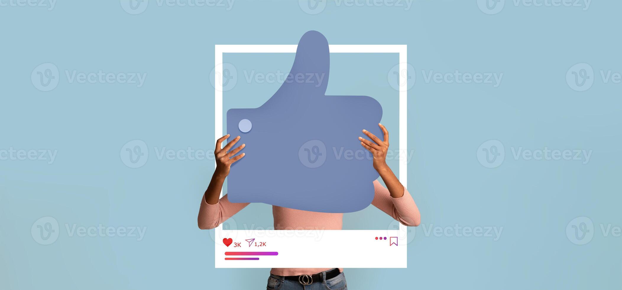 A person holds a large thumbs up symbol in front of a light blue background, symbolizing online approval. This display encourages interaction on social media platforms for content creators. photo