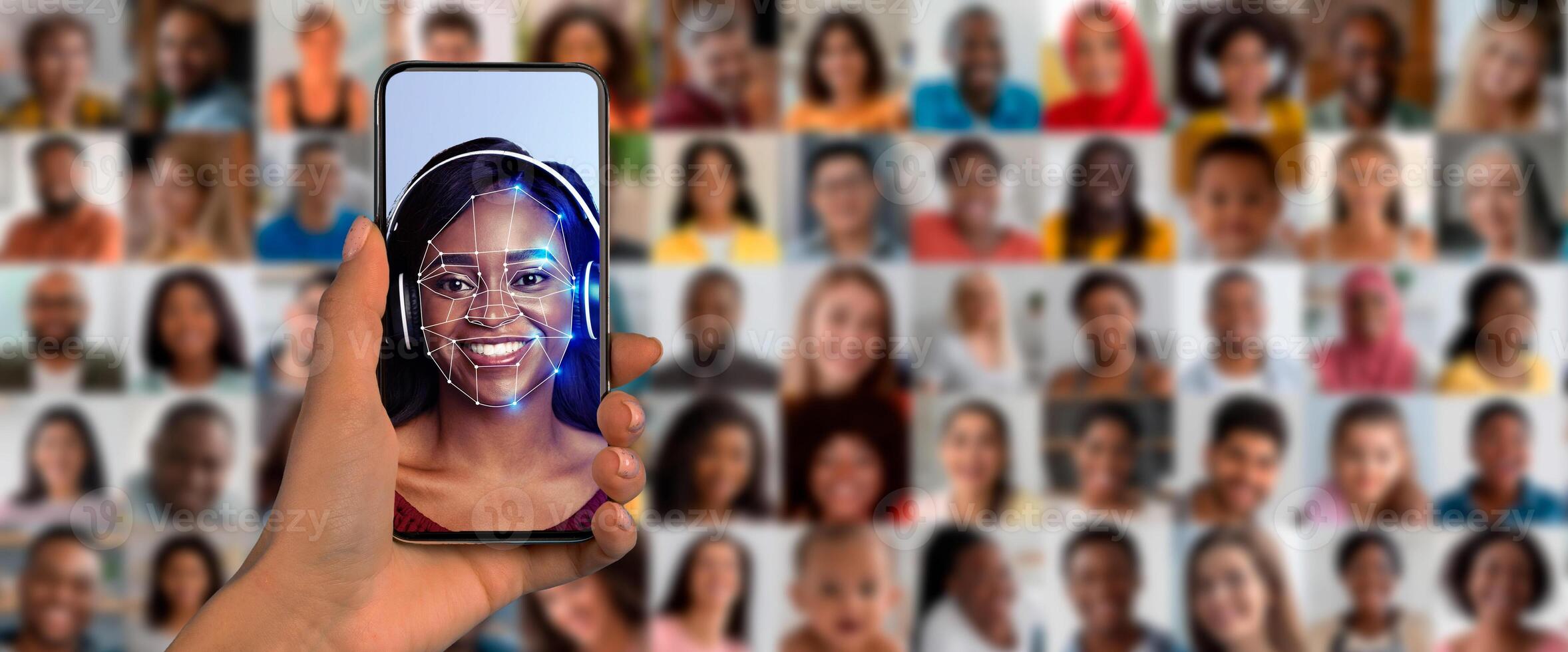A person holds a smartphone displaying a face recognition scan. The background is a collage of diverse faces. This modern technology showcases identification methods and security features. photo