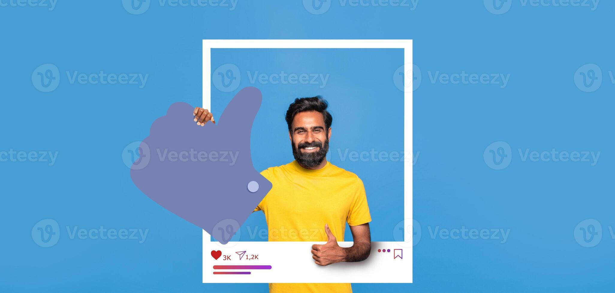 A smiling man in a yellow shirt stands against a blue background, showcasing positivity with a thumbs up gesture. He embodies the spirit of social media engagement and content creation. photo