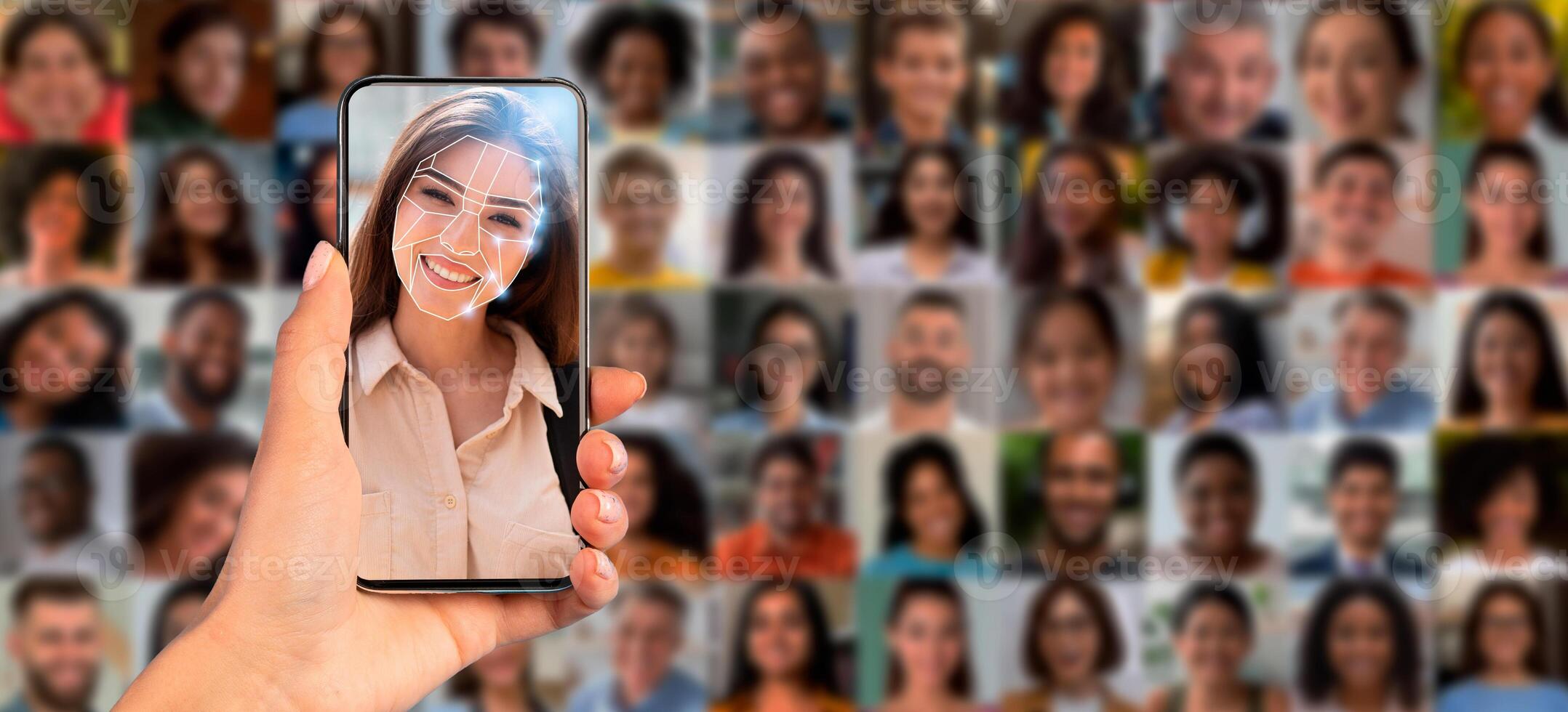A hand holds a smartphone displaying facial recognition technology, highlighting a person's face against a collage of diverse portraits, showcasing modern identification methods and technology. photo