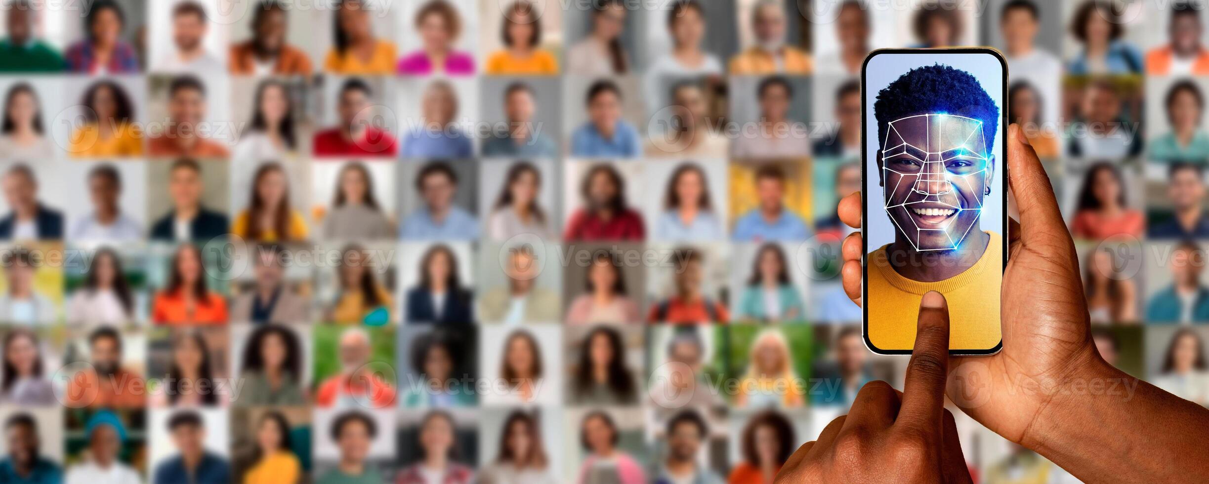 A hand holds a smartphone displaying a face scan of a smiling individual. Behind are numerous portraits of different people, emphasizing modern identification technology. photo
