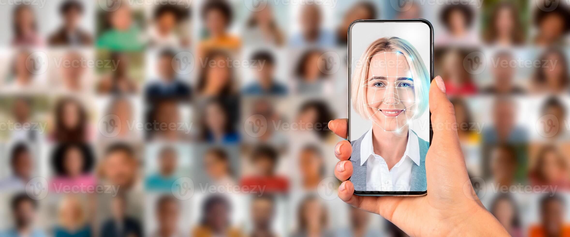A smartphone is held in a hand, displaying a face for identification against a backdrop of various portraits. This showcases modern technology used for facial recognition. photo