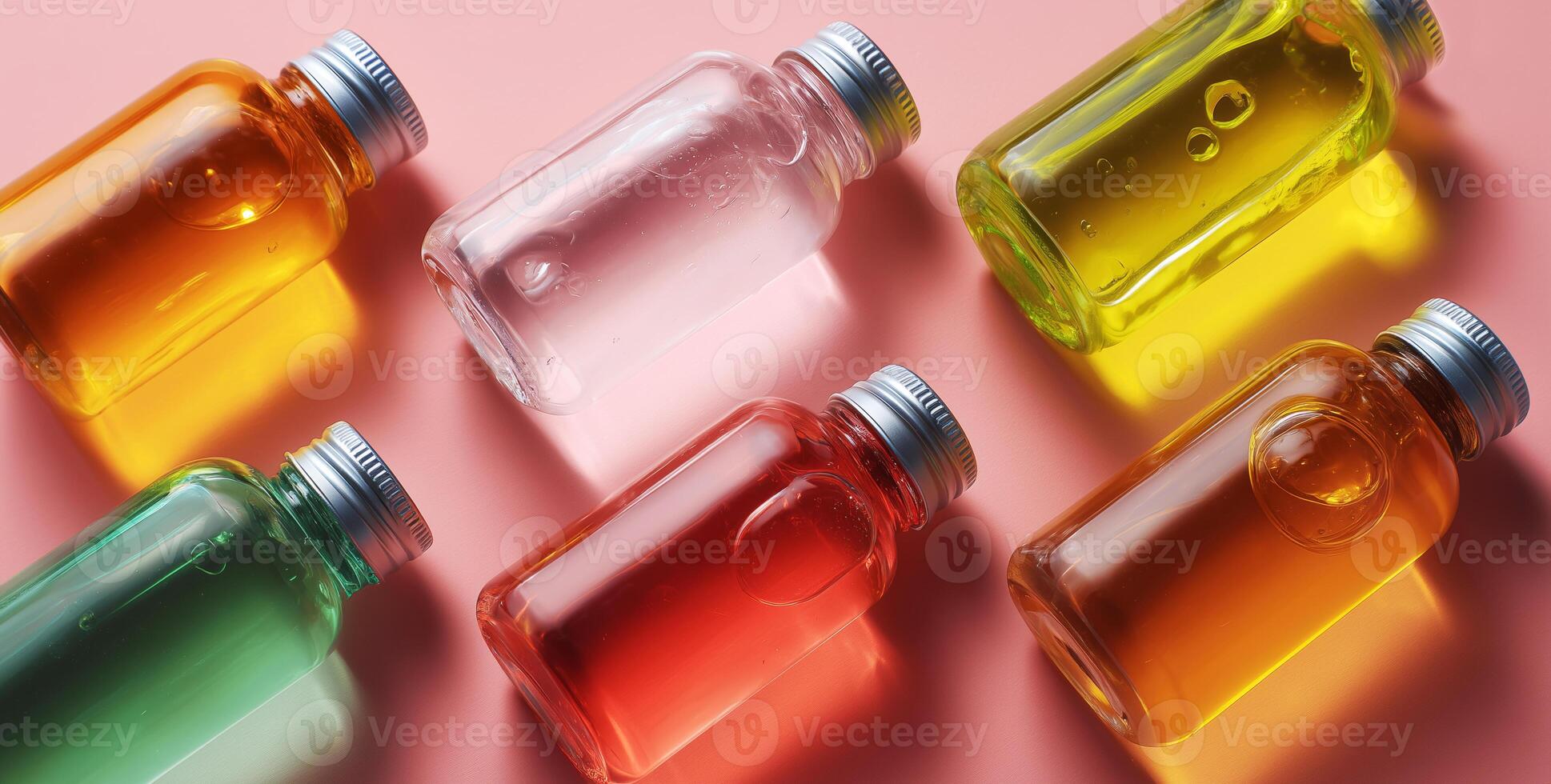 Various glass jars and bottles filled with colorful cosmetic serums are neatly arranged on a smooth pink surface. photo