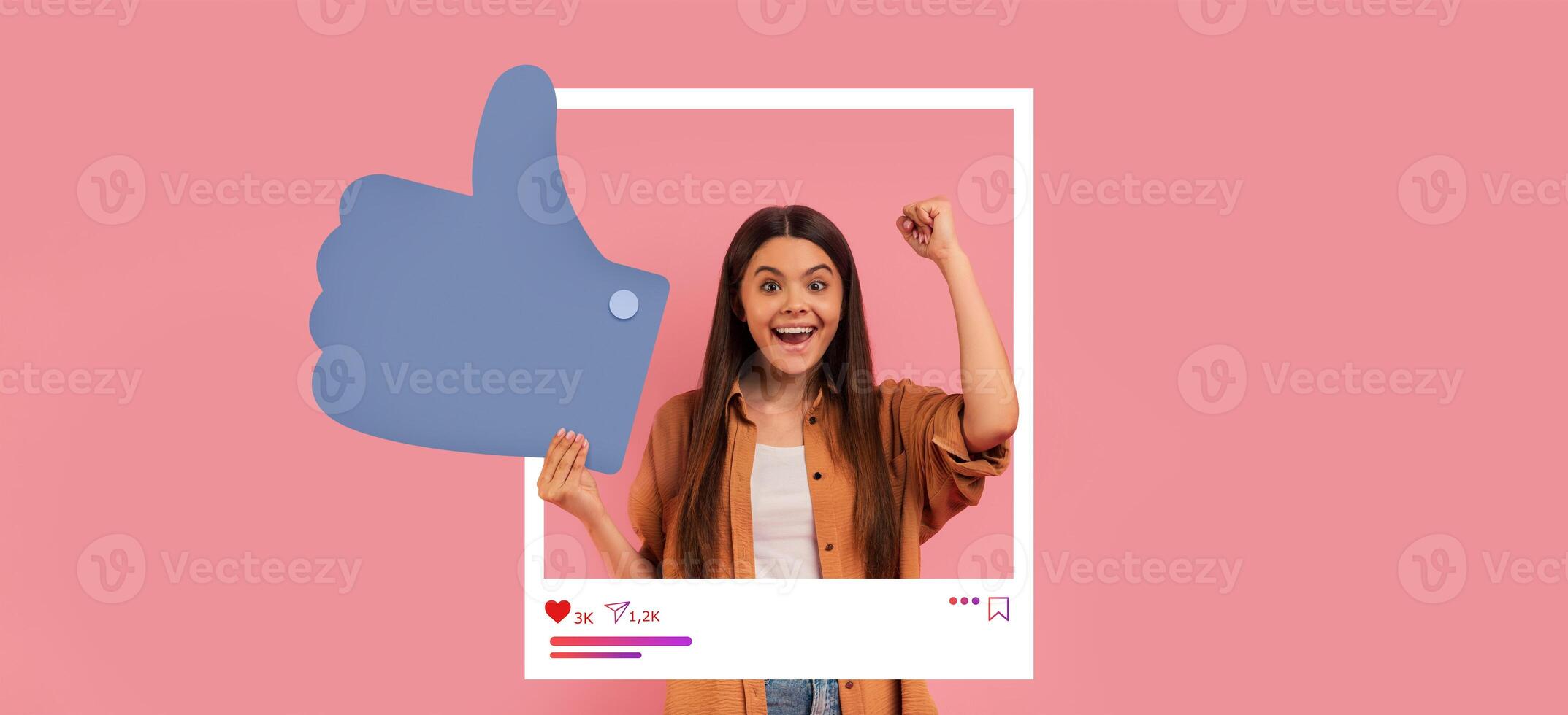 A young influencer expresses excitement while holding a large thumbs up symbol. Bright pink background enhances the celebratory mood, reflecting positive online interactions and content creation. photo