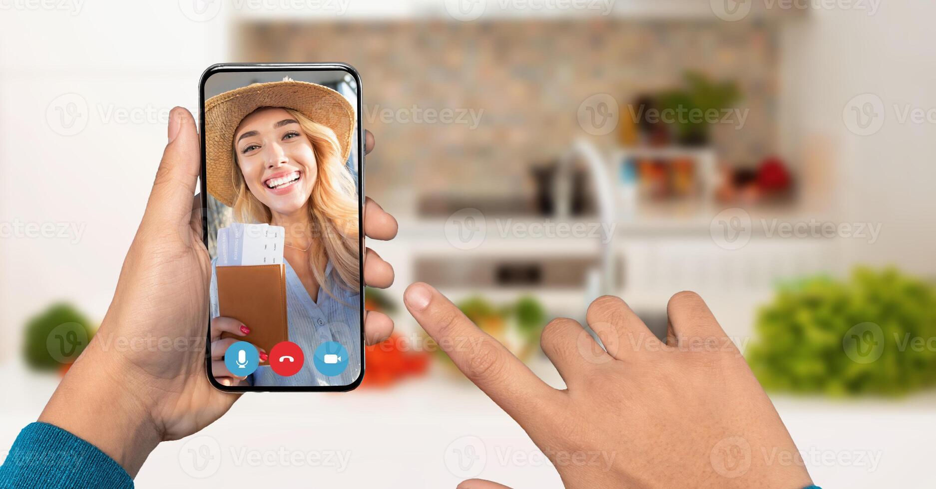 A person connects with cheerful young woman on a smartphone. The background features a cozy kitchen filled with greenery and home items. photo