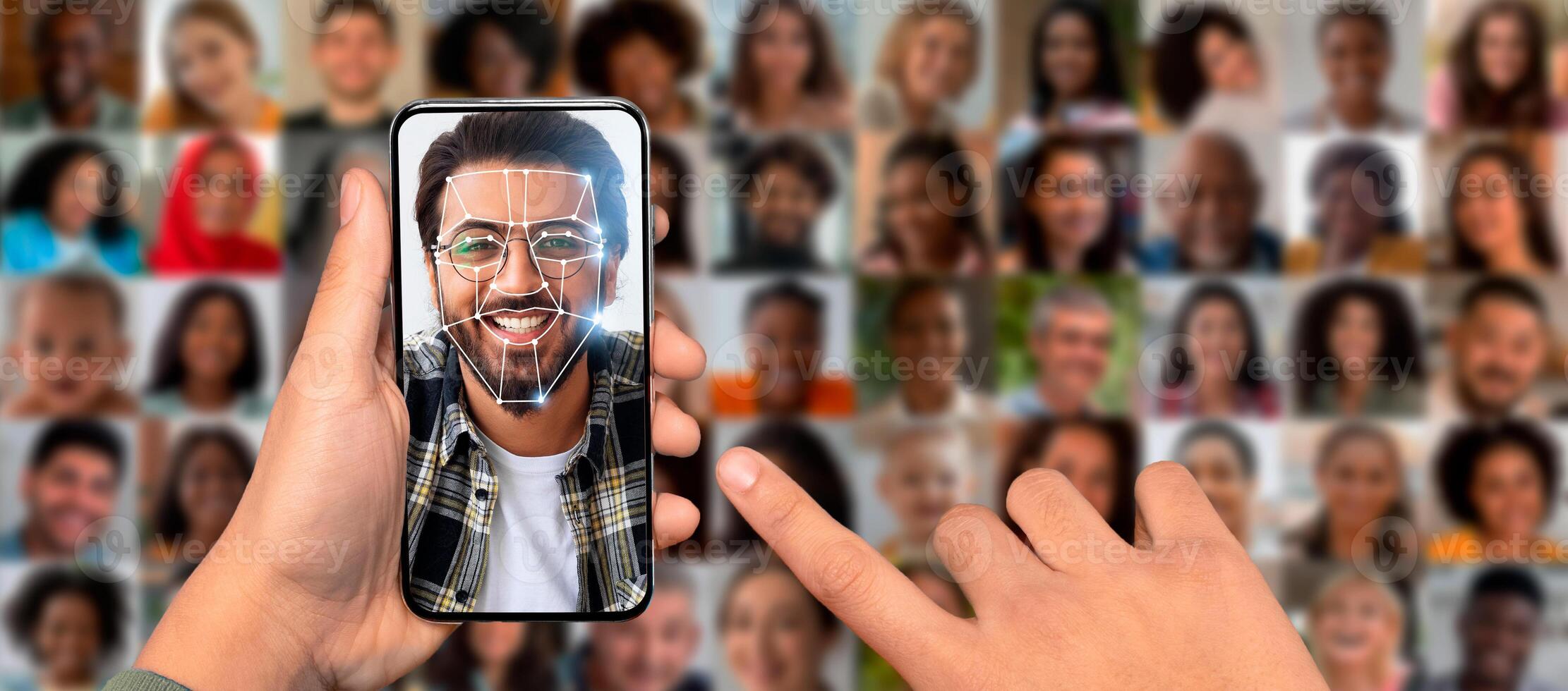 A person holds a smartphone displaying a facial recognition scan. Surrounding the individual are multiple portraits of diverse faces, showcasing advanced identification technology in everyday life. photo