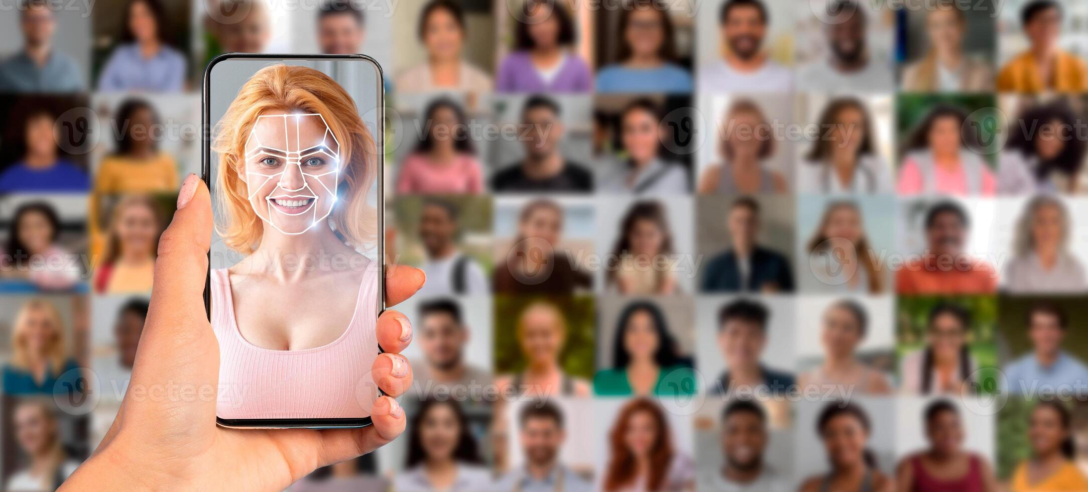 A person holds a smartphone displaying a face scan, with numerous portraits of different people in the background. This showcases the advancement in identification technology through mobile devices. photo