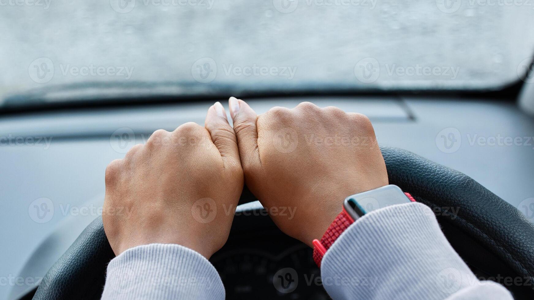 Modern woman driver and searching road by gps map. Hands of young african american lady with smart watch on steering in car with smartphone with empty screen in rainy weather, pov, free space, cropped photo