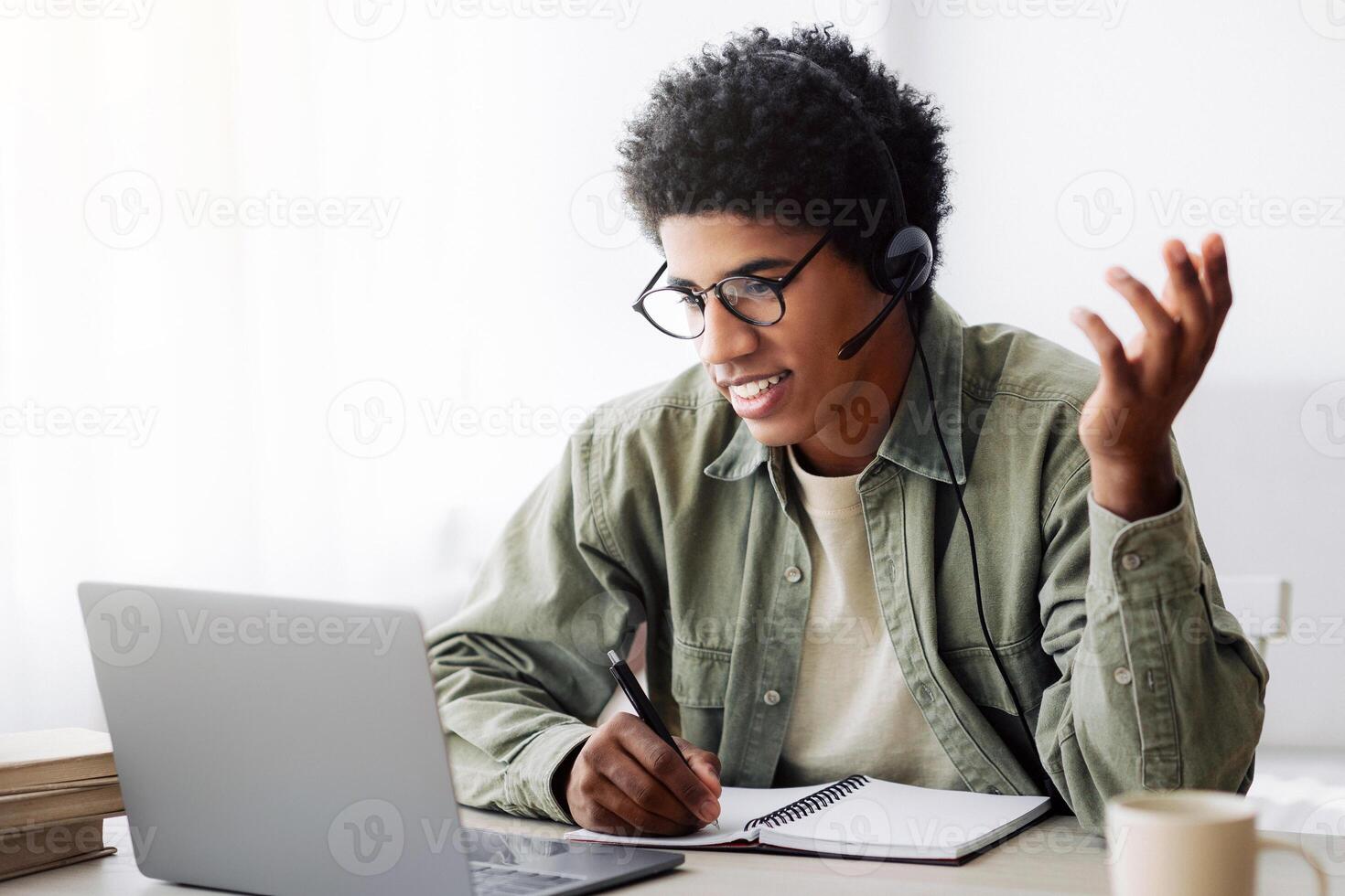 Online communication and web based learning. Positive black teenager speaking to his college tutor on laptop from home. Handsome African American student making call on webcam photo