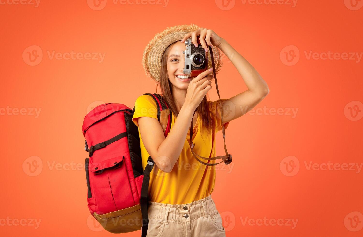 Active girl backpacker taking photos over yellow studio background, active resting concept