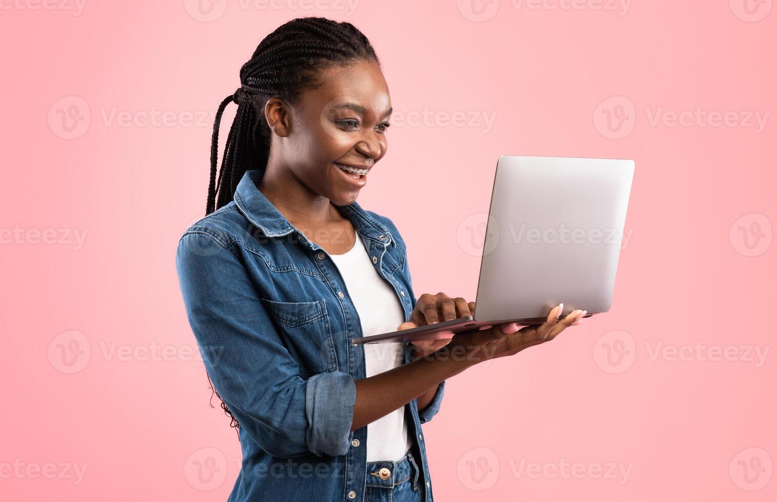 Cheerful Black Woman Using Laptop Standing On Pink Background. Computer User Concept. Studio Shot photo