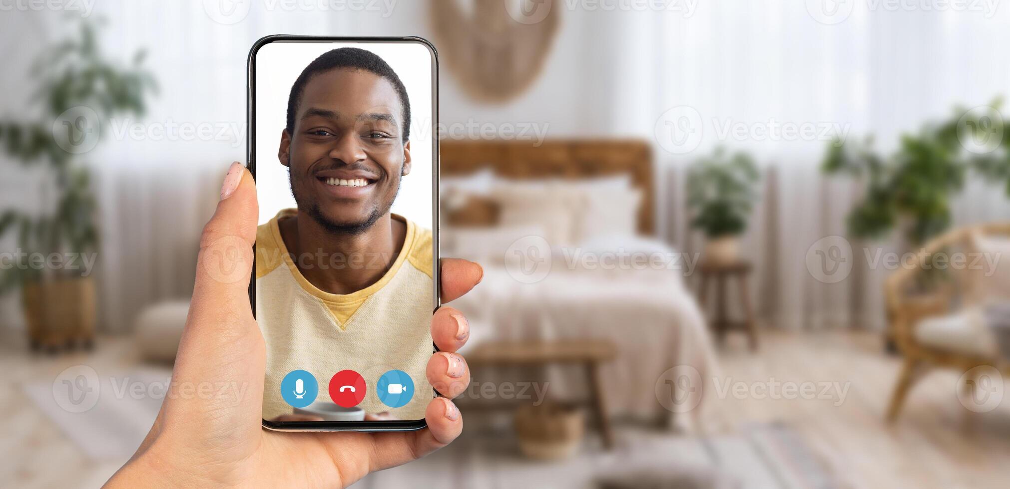 A person smiles on a call via smartphone, surrounded by soft lighting and decor, creating a warm and inviting atmosphere for comfortable communication. photo