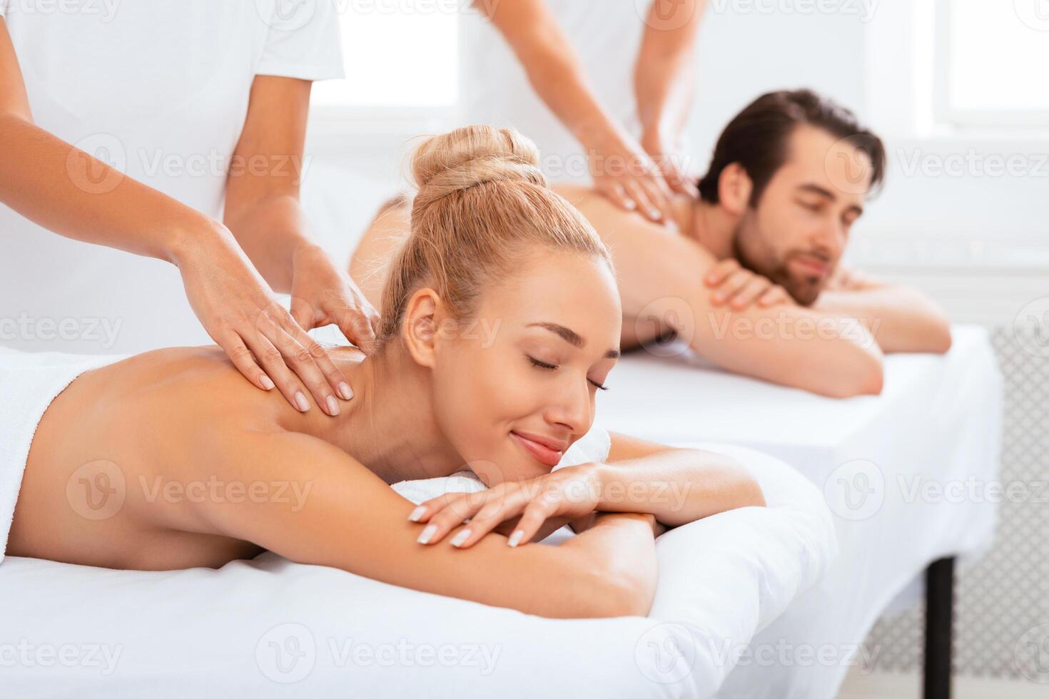 Couples Massage. Relaxed Spouses Enjoying Procedure Lying In Masseur's Chair At Spa Resort Indoor, With Eyes Closed. Romantic Beauty Wellness Treatment For Two, Massaging Therapy. Selective Focus photo