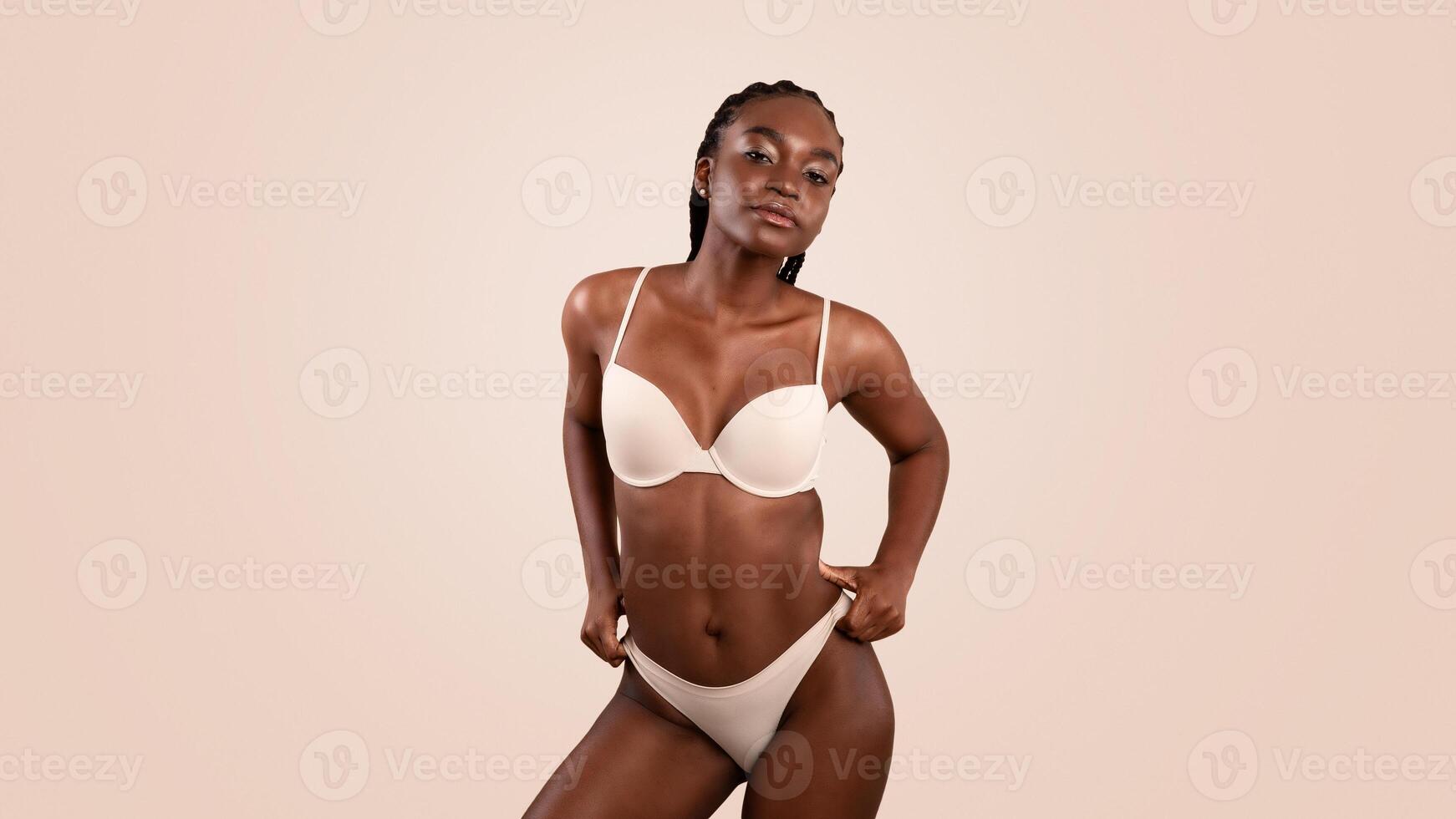 Portrait Of Sporty Fit Young Black Lady Posing In Lingerie Over Beige Background, Slim African American Woman With Smooth Skin Standing In Studio, Enjoying Her Beauty, Free Space photo