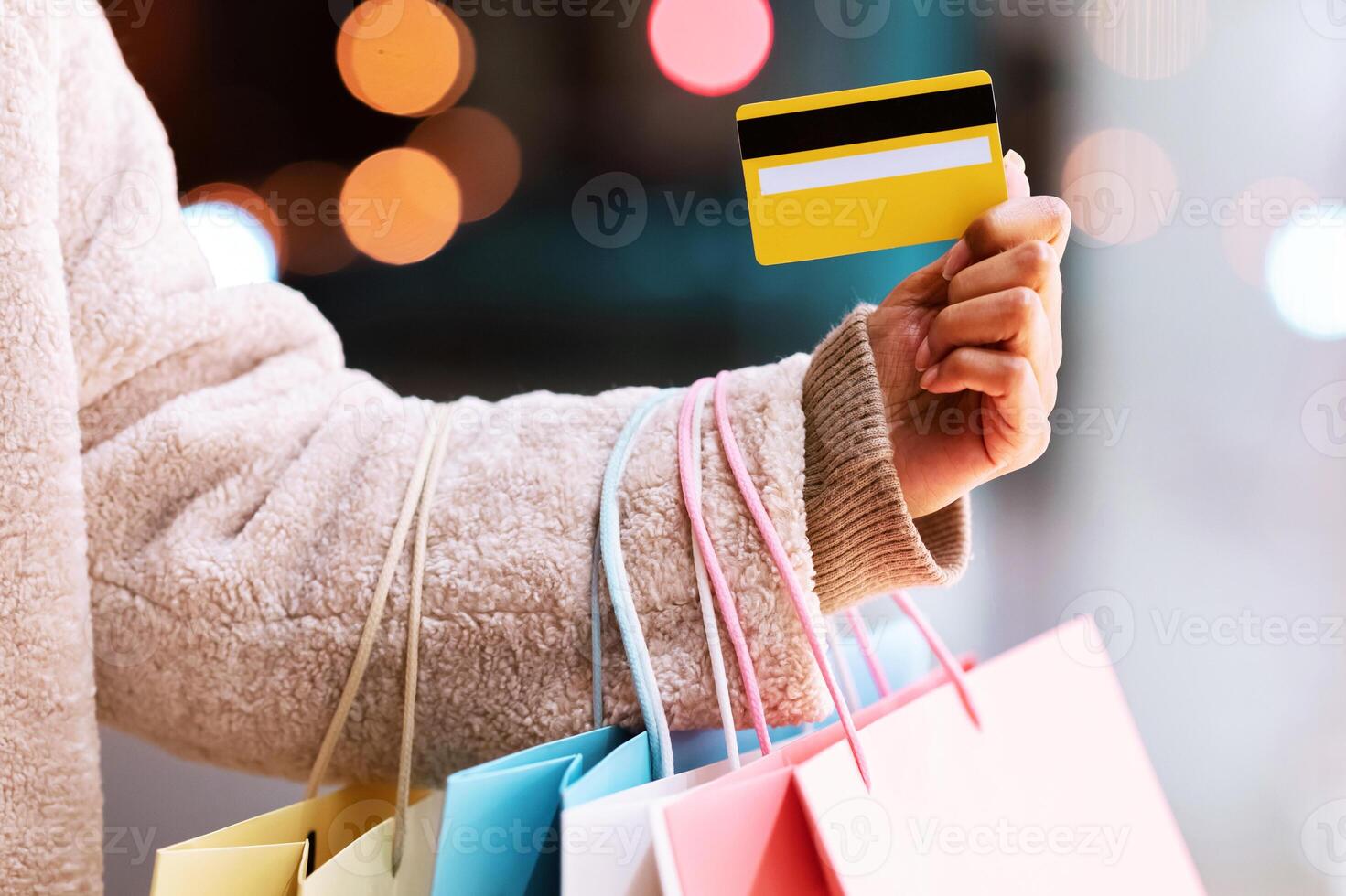 Easy Payment Concept. Closeup Of Unrecognizable Black Woman In Winter Coat Holding Credit Card And Bright Colorful Shopping Bags From Mall, Standing Outdoors In The Evening. Retail And Purchase photo