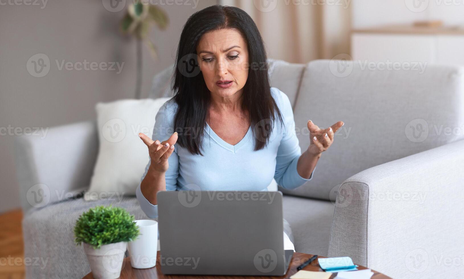 Call. Serious Female Entrepreneur Having Web Conference On Laptop, Working At Home Office During Quarantine, Sitting On Couch At Desk, Talking At Camera, Gesturing. Distance Communication photo