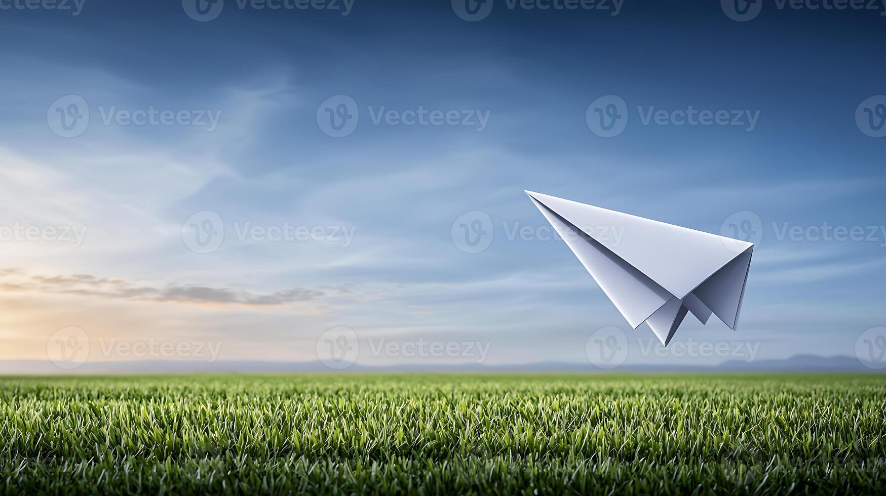 A paper airplane soaring over a green field at sunset, symbolizing freedom and creativity photo