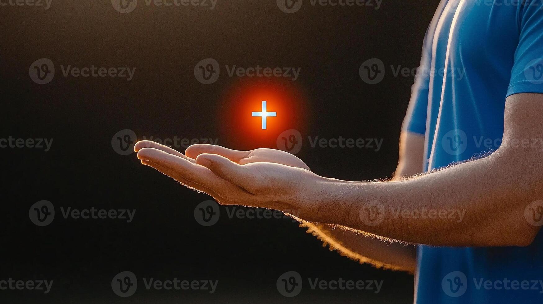A person with outstretched hands under a sunset, symbolizing hope and faith with a glowing cross photo