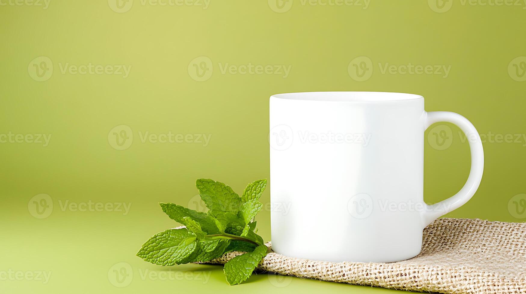 A plain white mug placed on a burlap mat with fresh mint leaves against a green backdrop photo