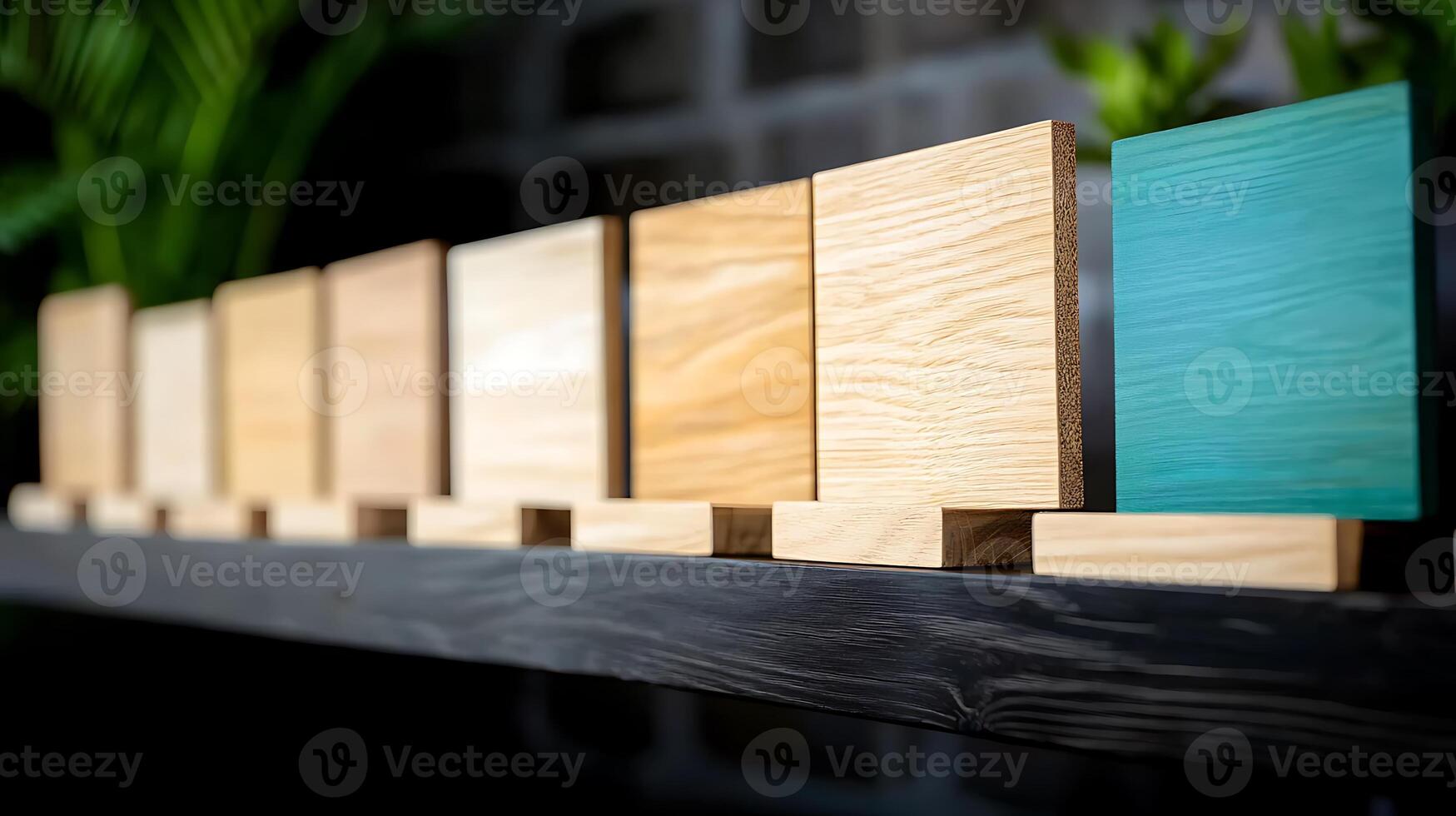 A row of wooden blocks in various shades arranged on a shelf with greenery in the background photo