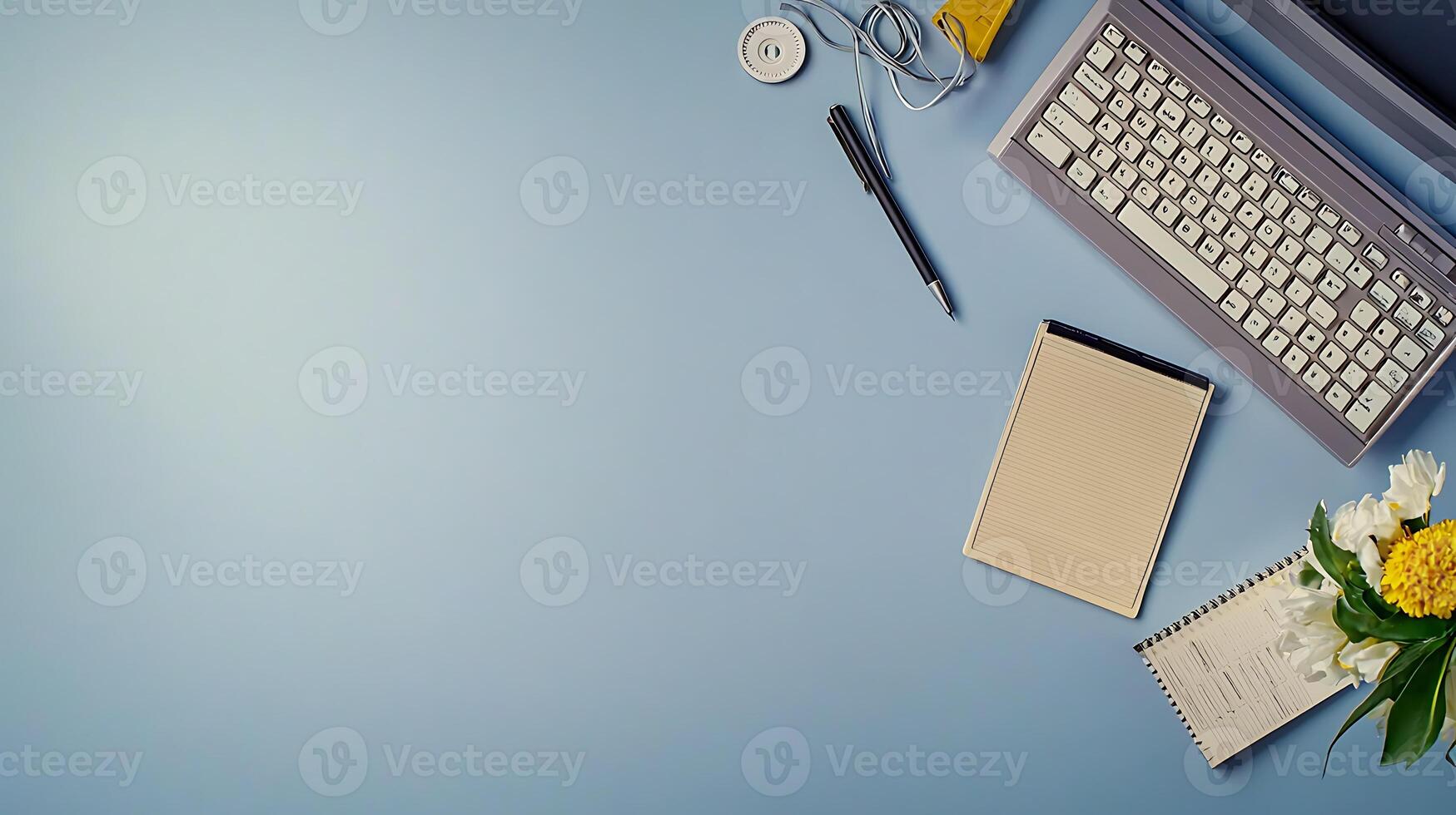 A serene workspace featuring a keyboard, notepad, and flowers on a blue background photo