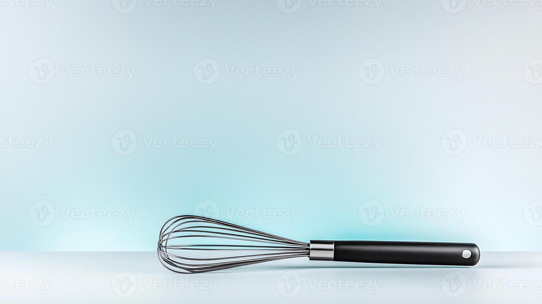 A sleek stainless steel whisk resting on a minimalist countertop with a soft blue gradient background photo
