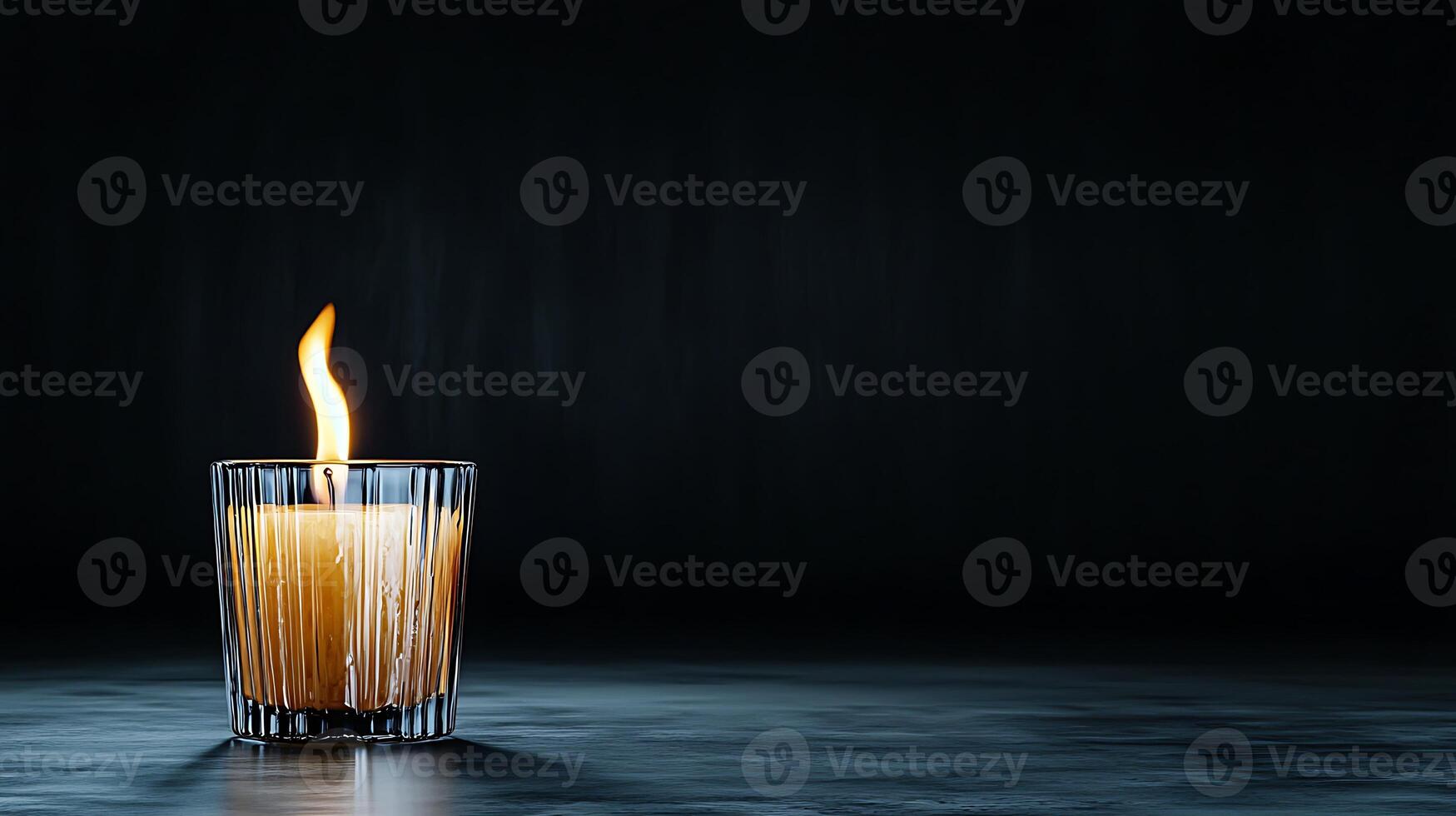 A solitary candle flickers in a dark setting, casting warm light and shadows around photo