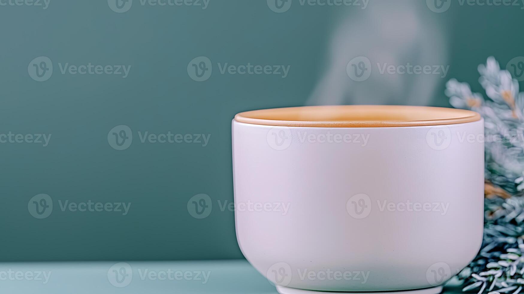 A steaming cup of tea placed on a minimalist table with a sprig of greenery in the background photo