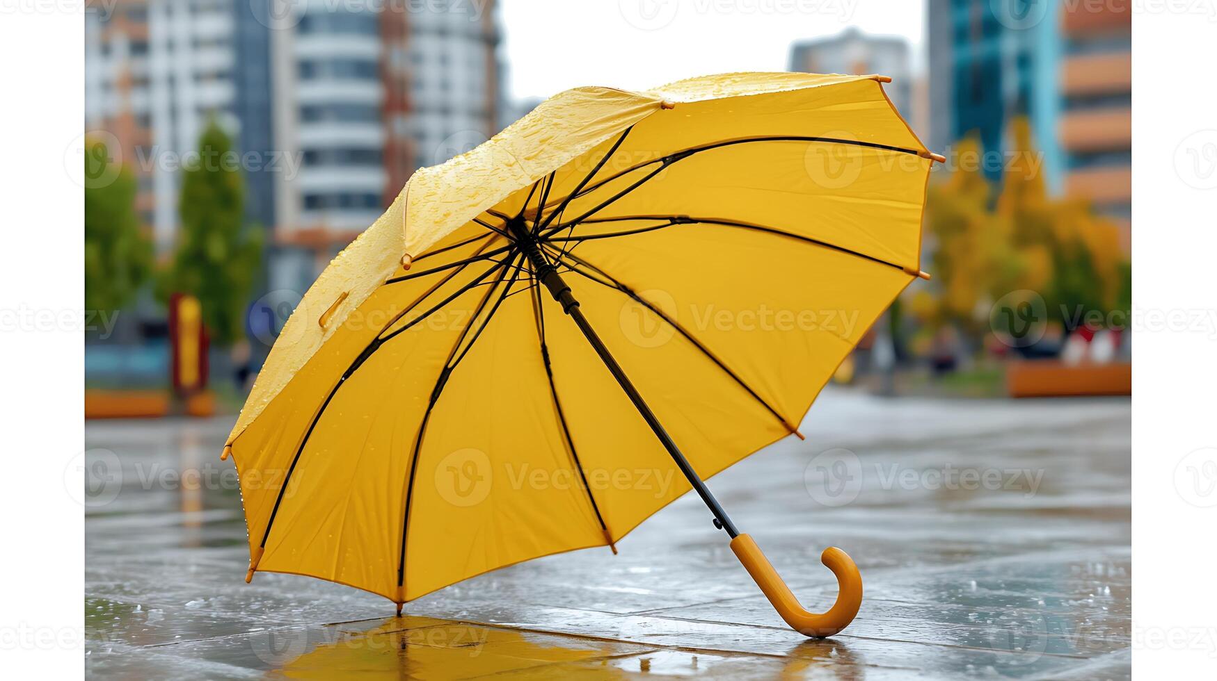 A vibrant yellow umbrella stands alone on a rainy city street, reflecting urban buildings and trees photo