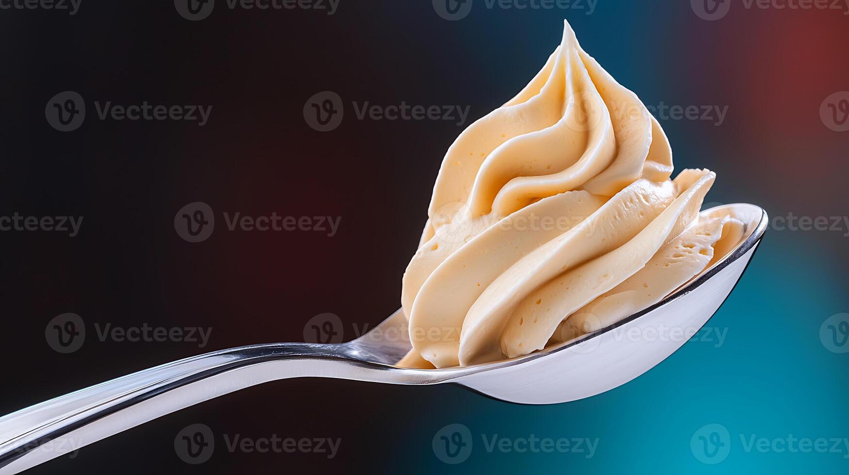 Close-up of a creamy swirl of butter on a silver spoon against a blurred colorful background photo