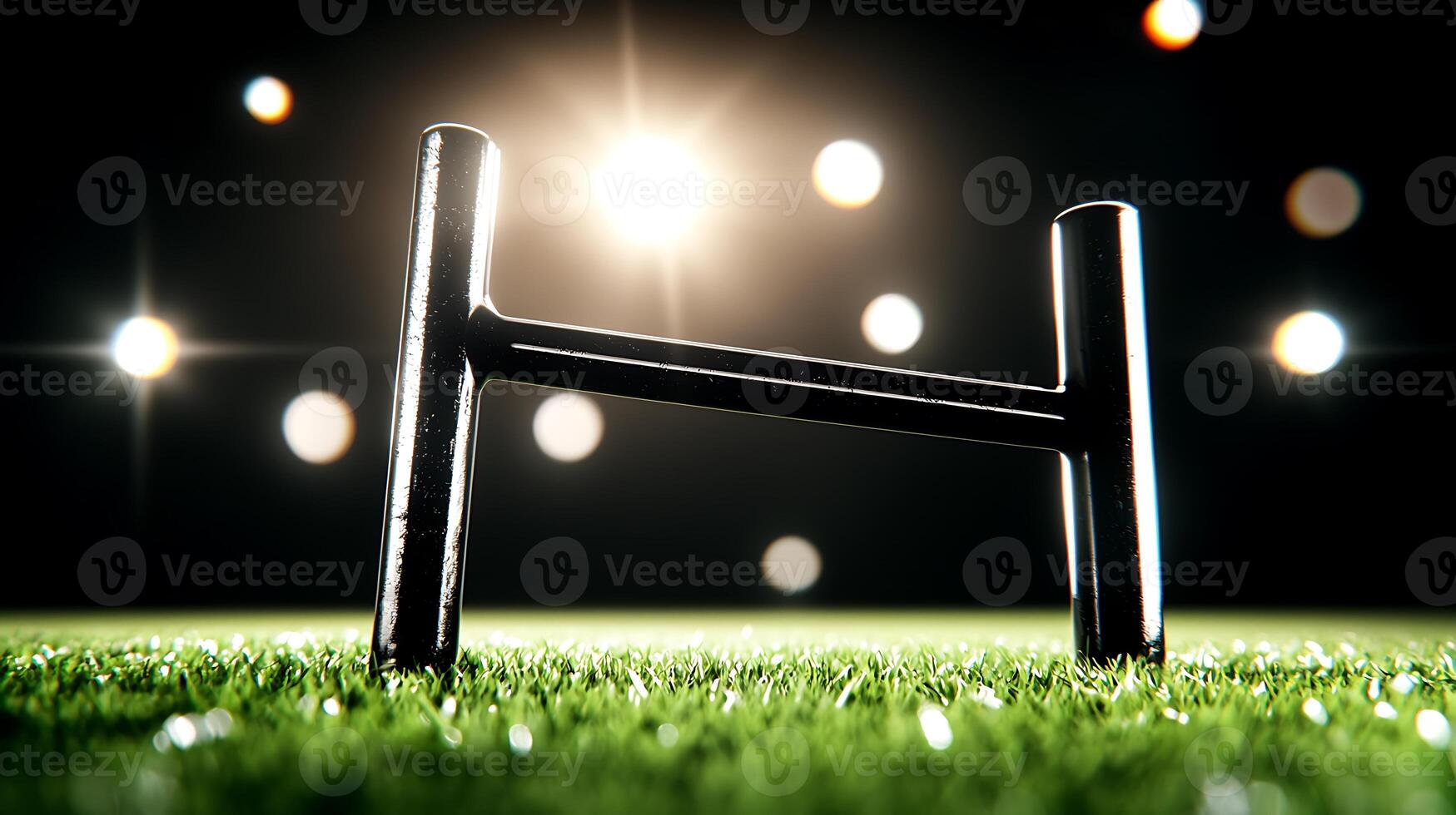 Close-up of a rugby goalpost on a vibrant green field under bright stadium lights at night photo
