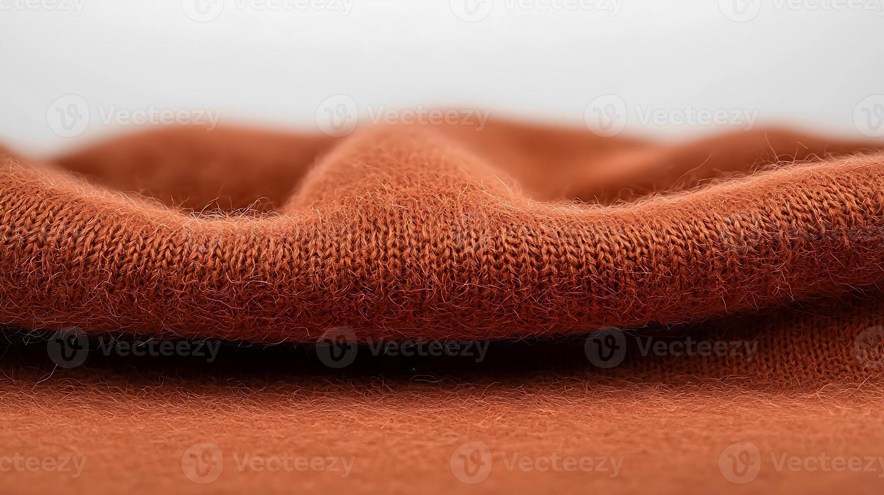 Close-up view of soft, textured fabric in warm orange hue, highlighting its intricate weave and folds photo