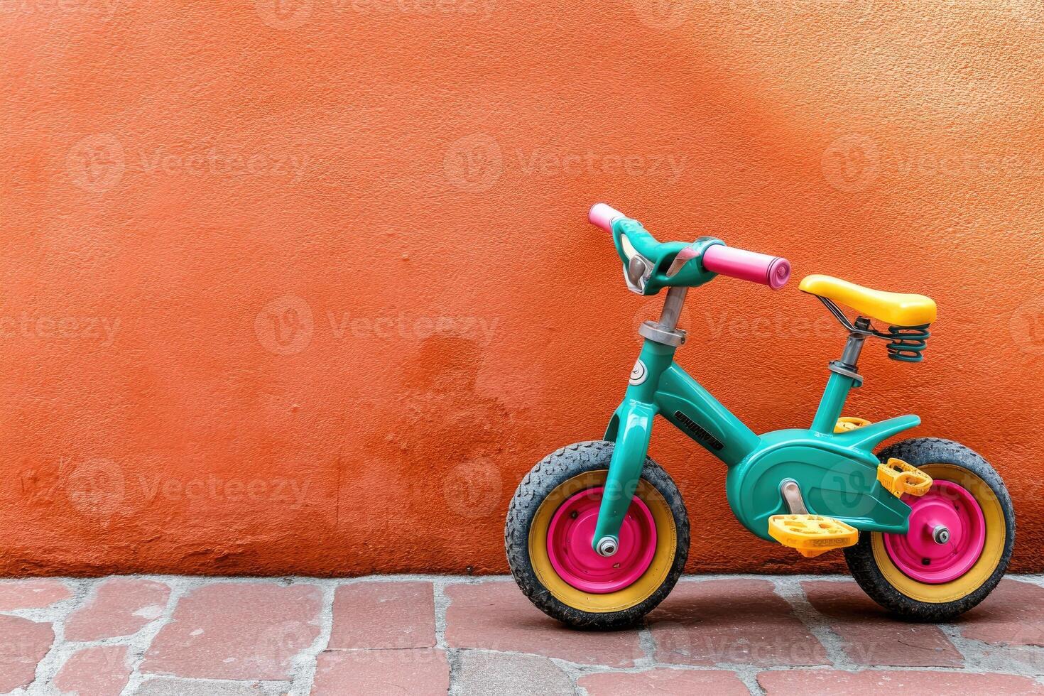 Colorful children's balance bike against orange wall photo