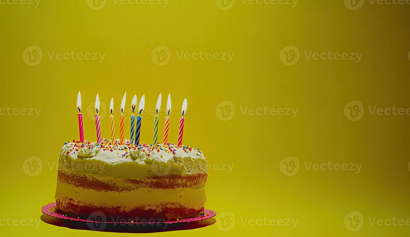 Birthday cake with colorful candles on a yellow background photo