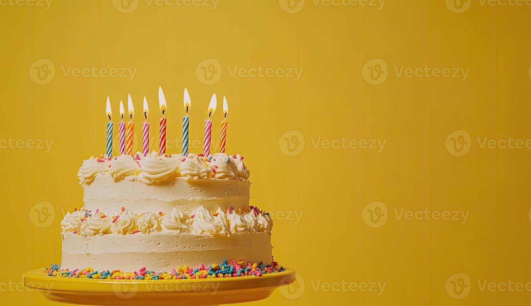 Two-tiered birthday cake with colorful candles on a yellow stand photo